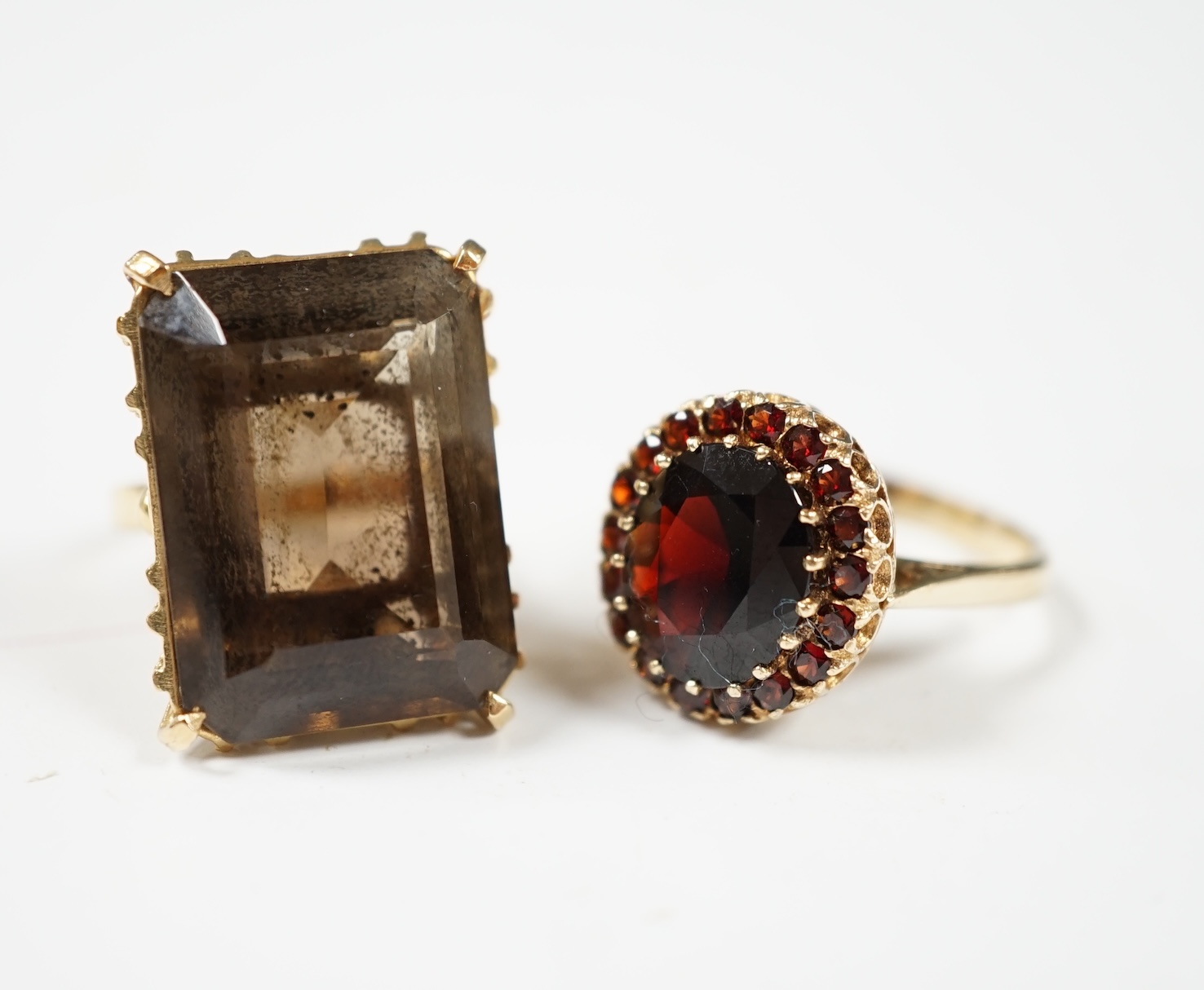 A 1970' 9ct gold and garnet set oval cluster ring, gross 5.5 grams, together with an 18k gold and smoky quartz set ring, gross 10.4 grams. Condition - fair to good